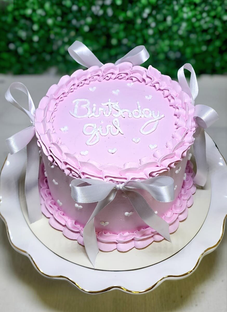 Bolo de aniversário rosa decorado com babados de chantininho e laços de cetim