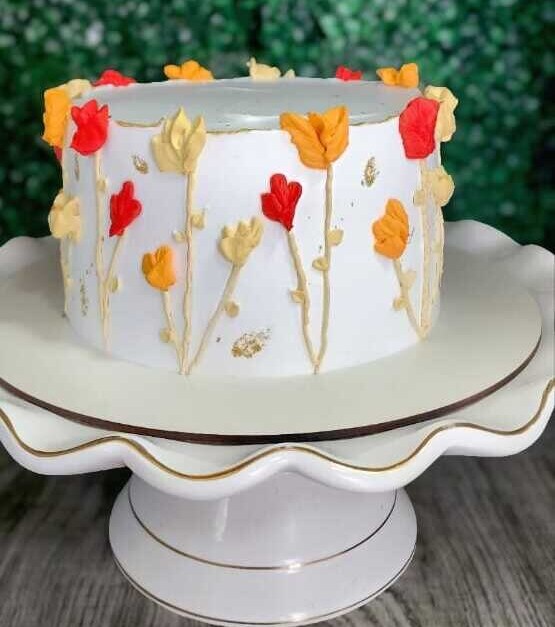 Bolo branco com flores em tons de laranja e dourado